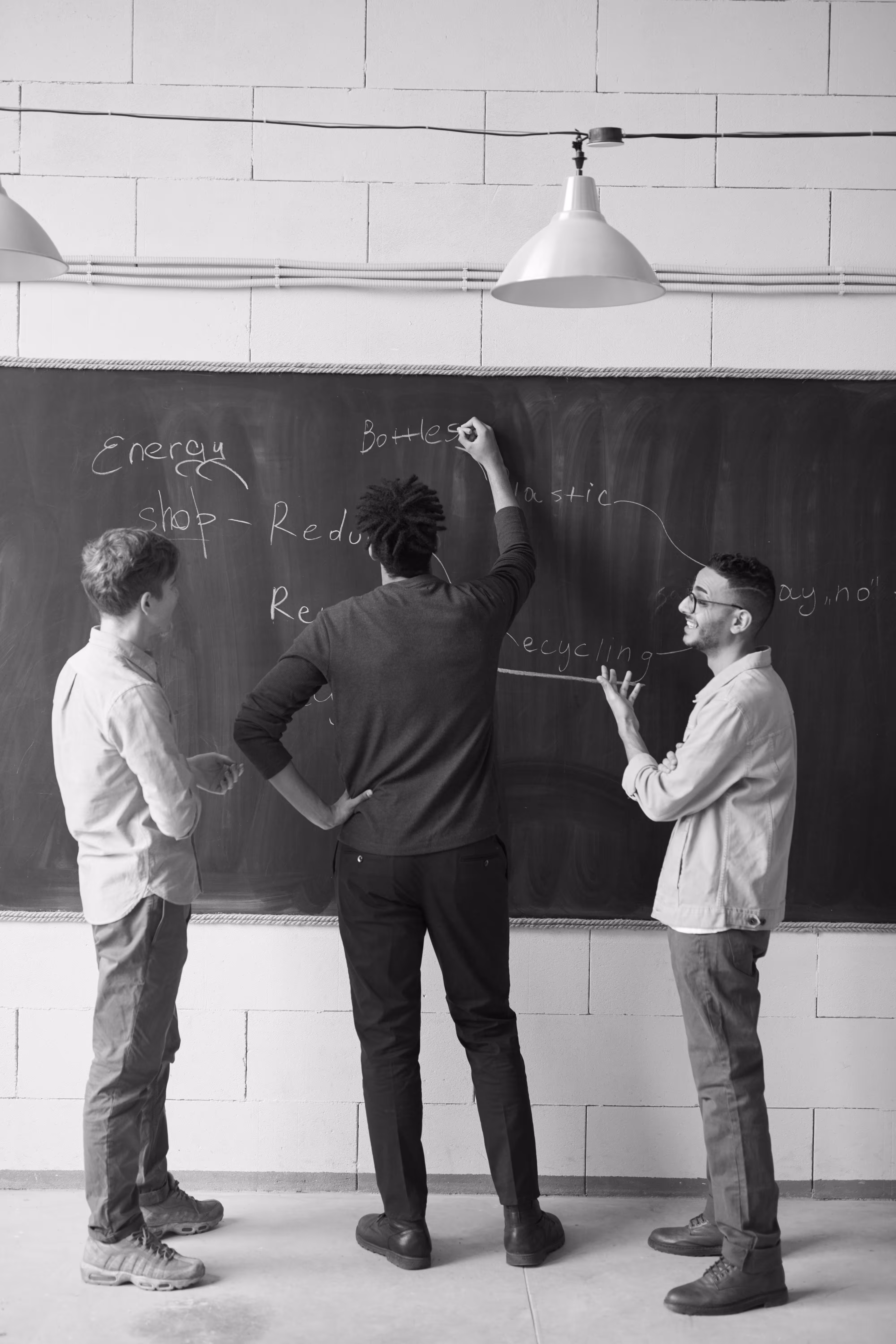 Personnes collaborant devant un tableau noir