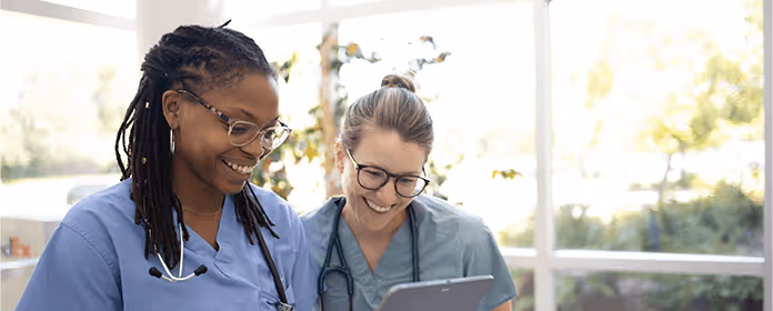 Picture of Osose watching a tablet with a colleague