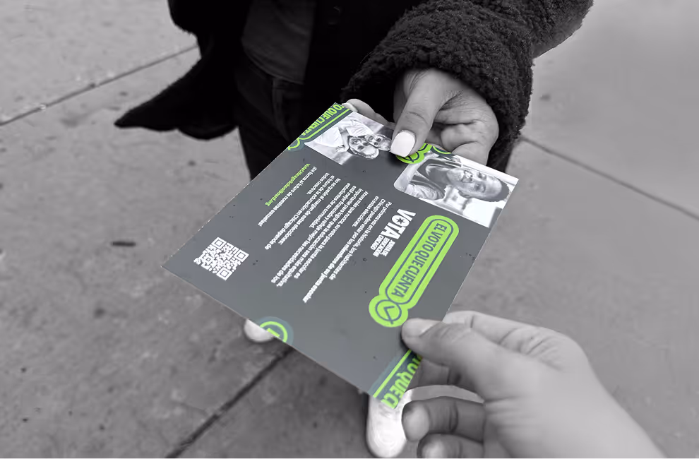 Two people exchanging a flyer on a sidewalk, with the flyer displaying text, images, and a QR code in green and white colors.