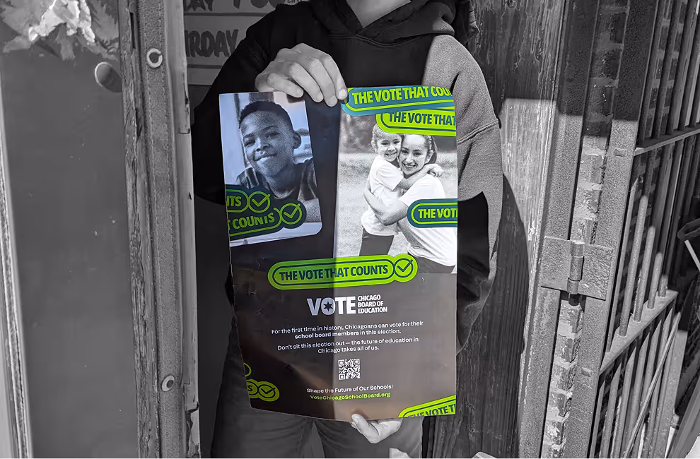 Person holding a poster urging Chicagoans to vote in the school board election featuring photos of children and text 'The Vote That Counts'.