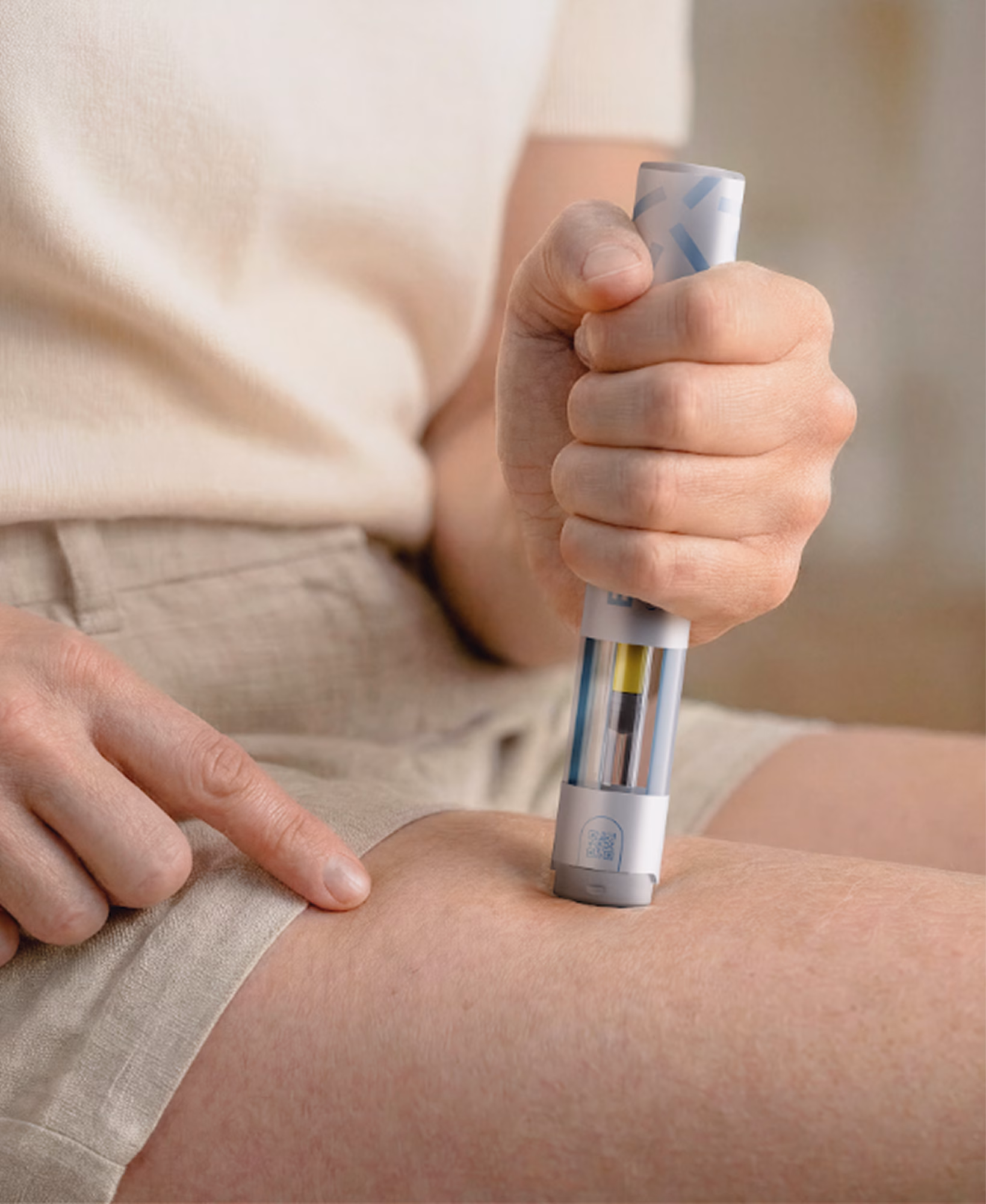 Person holding an EcoInject pen injecting medication into their thigh.