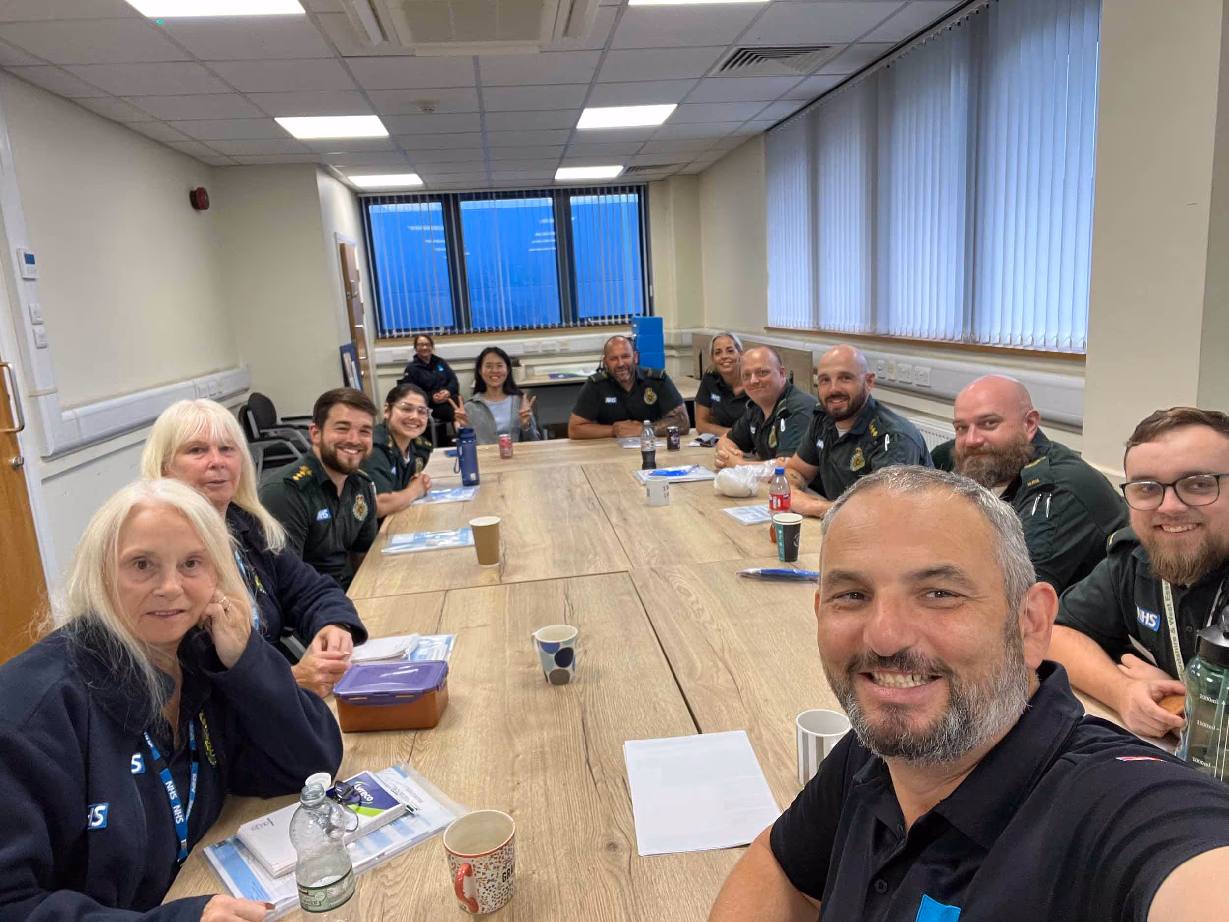 A group of people sitting around a conference table, smiling for a photo.