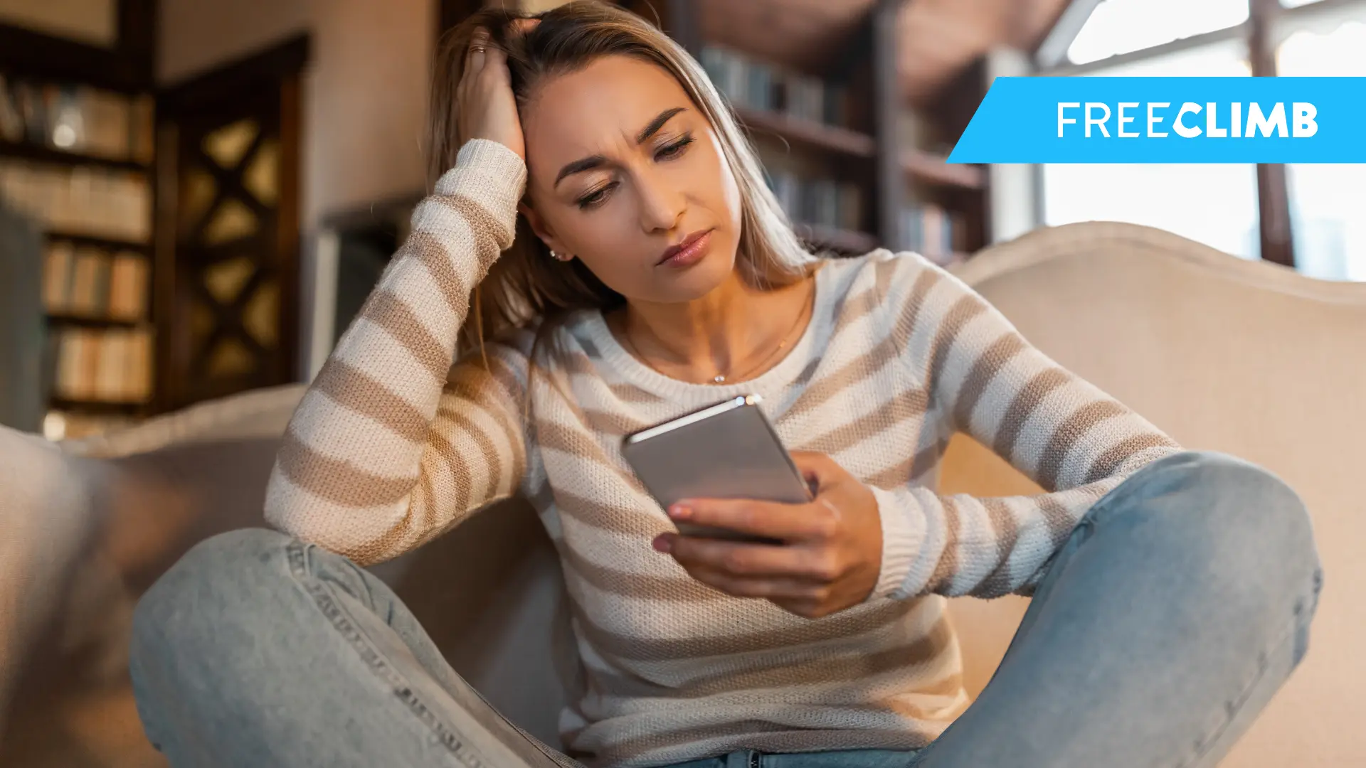 Women sits looking at her phone with frustration