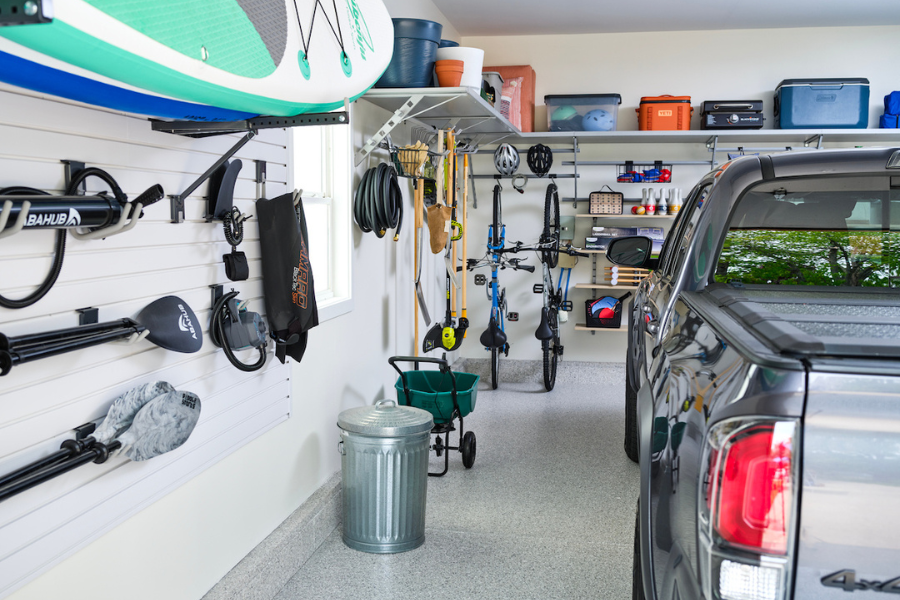 Well-organized garage featuring slatwall storage for outdoor gear, overhead shelves, bikes, and a parked truck.