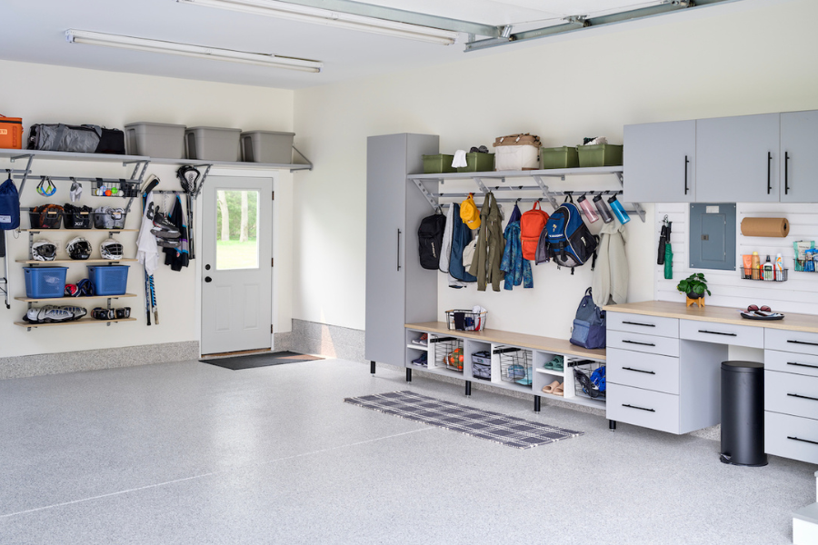 Spacious garage with wall-mounted cabinets, open bench seating, hooks for coats and backpacks, and overhead storage bins.