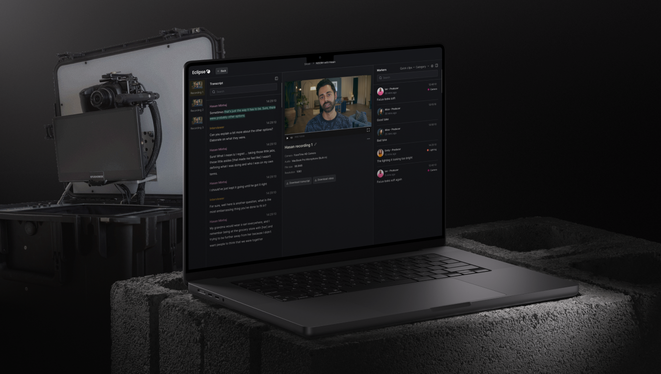 Laptop on concrete blocks displaying video editing software with transcript and video preview, next to a professional camera rig in a padded case.