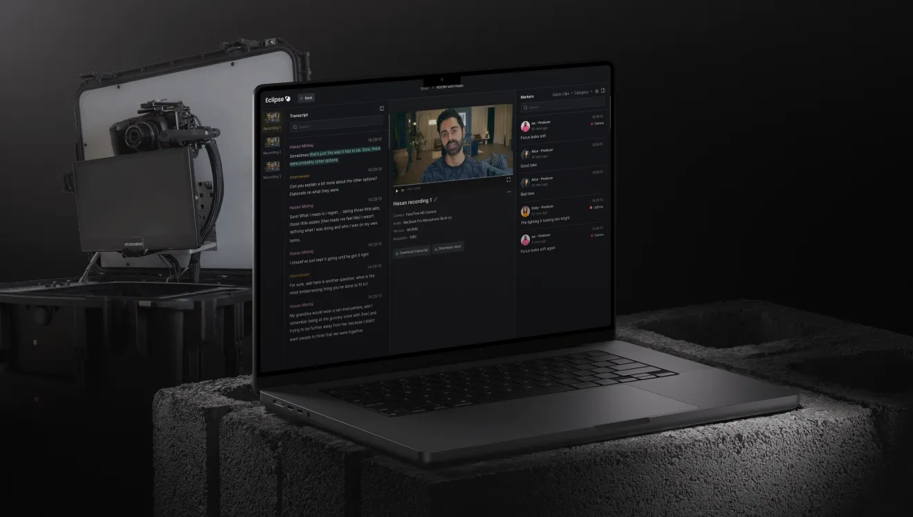 Laptop on concrete blocks displaying video editing software with transcript and video preview, next to a professional camera rig in a padded case.