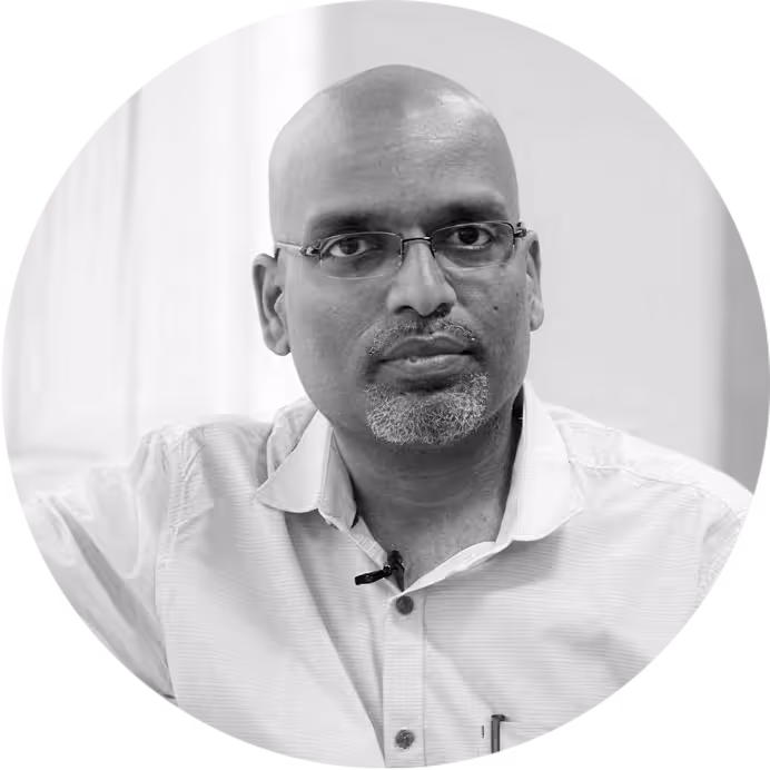 Portrait of a bald man with glasses and a goatee wearing a light-colored shirt and looking at the camera.