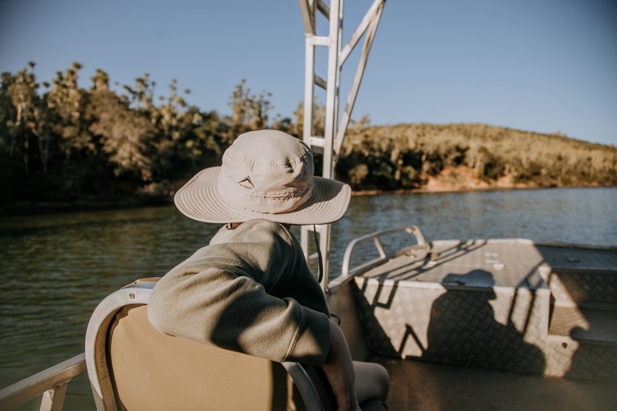 A guest in a bush hat looking out over the river from the cruise boat