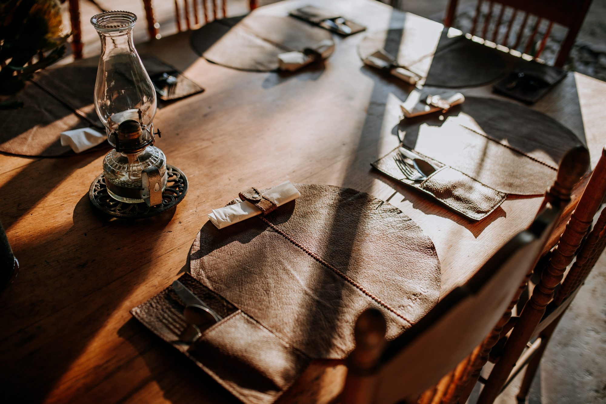 The mess tent table set with leather placemats and a paraffin lantern