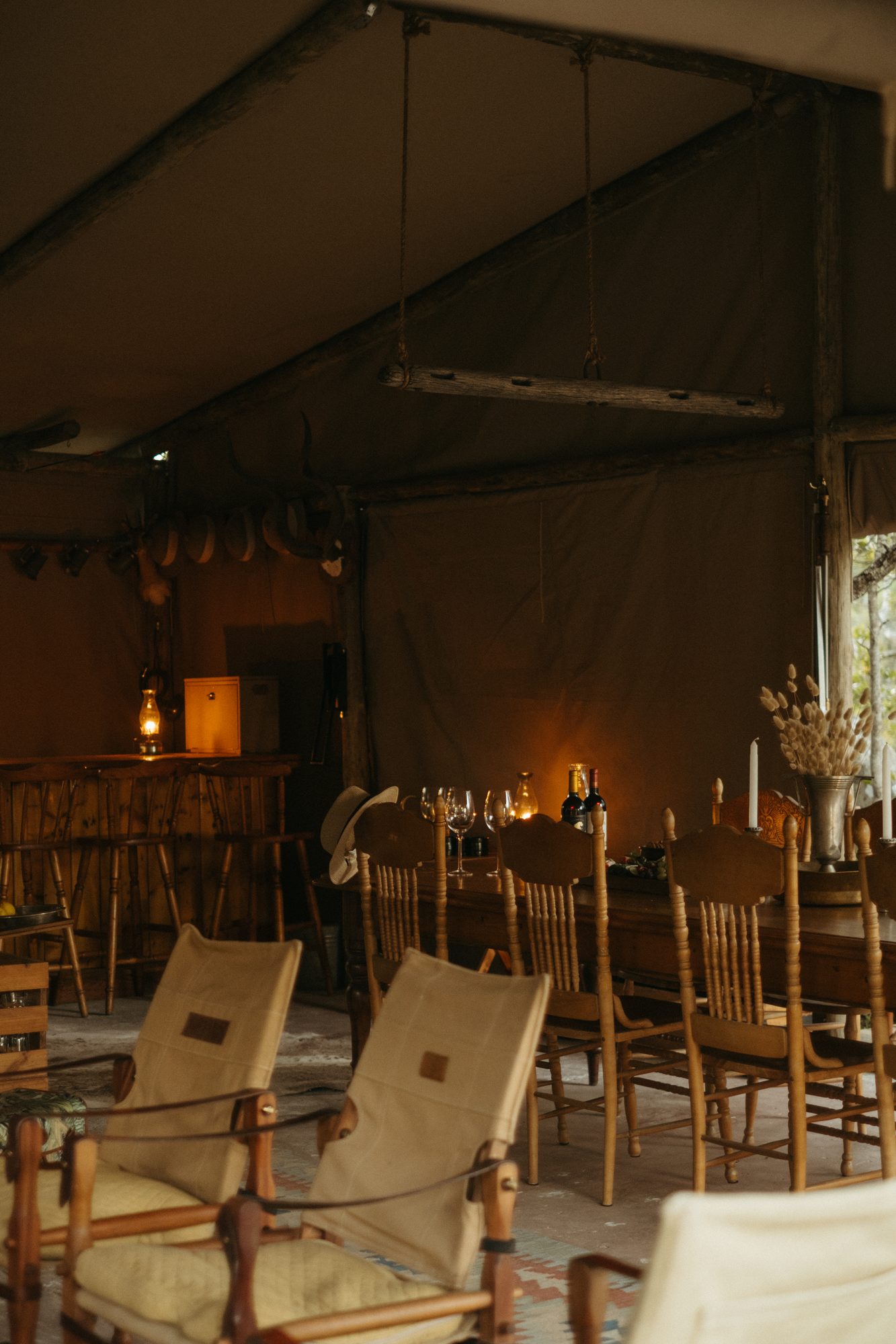 The mess tent at dusk, the long table set with wine and candles beside the bar
