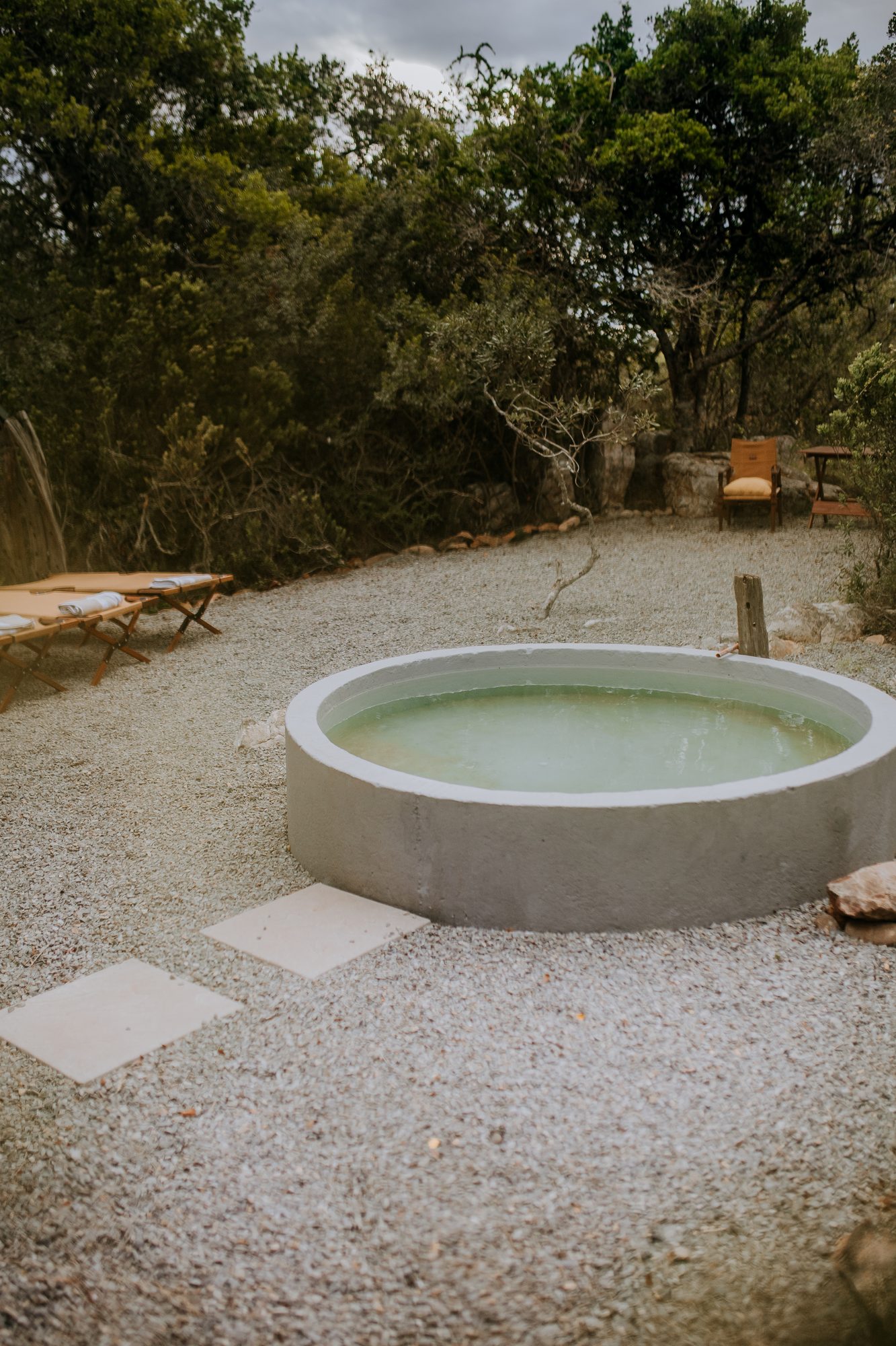 The round splash pool on a gravel terrace, loungers beside it