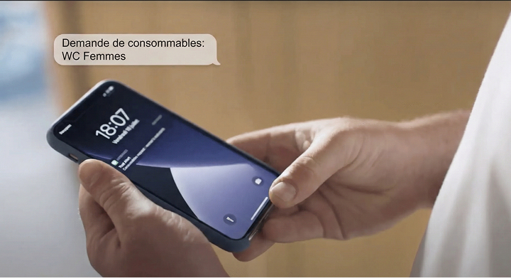 Un agent d'entretien reçoit une notification sur son smartphone "Demande de consommables: WC Femmes"