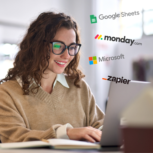 A woman looking at her computer with the Google Sheets, monday.com, Microsoft and Zapier logo floating around