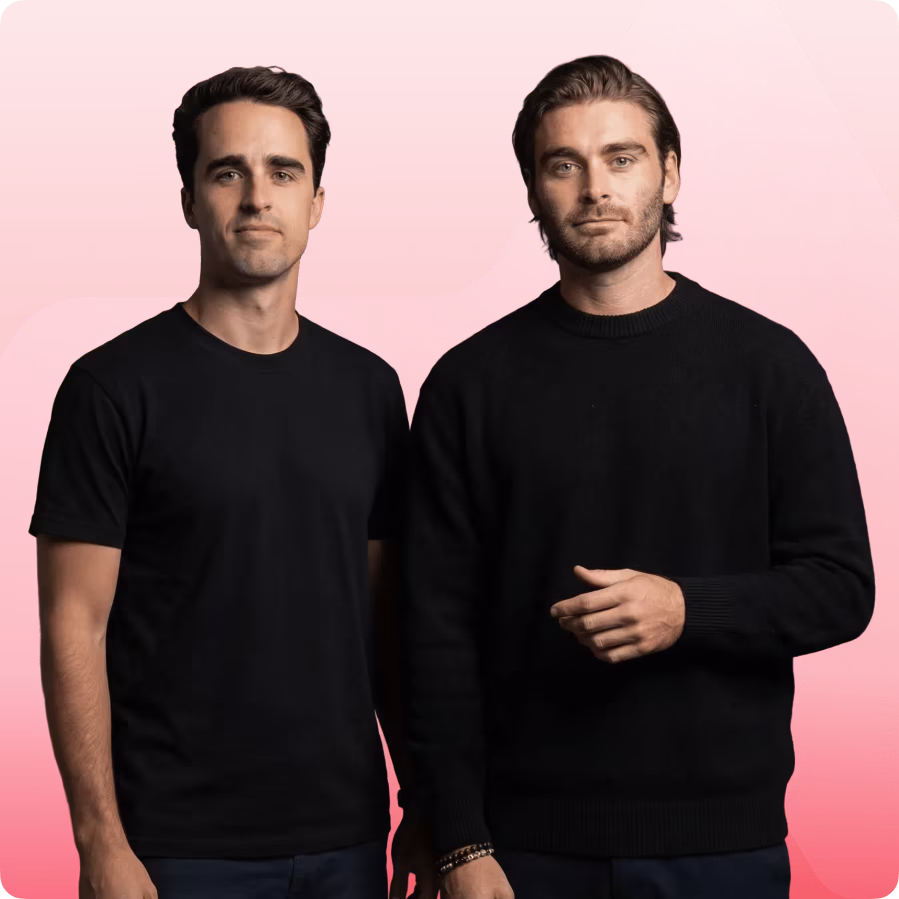 Two men with short dark hair wearing black tops standing side by side against a red and pink background.