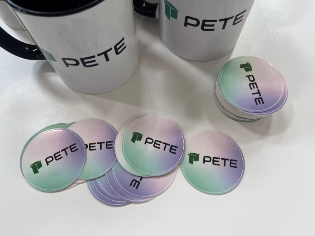 A picture showing several PETE-themed stickers and mugs, with PETE's logo on them.