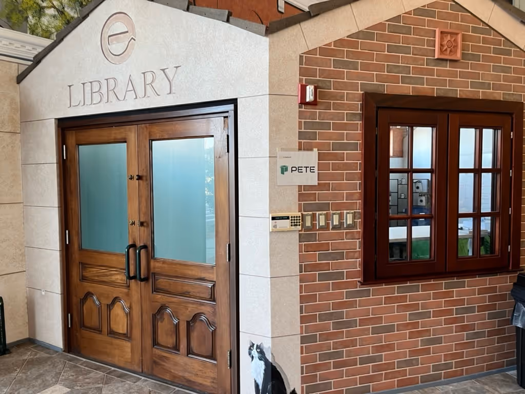 A picture of PETE's office space in Orlando, showing the outside front wall. It shows a brick-house themed storefront, made to look like a library. There is a sign that shows PETE's logo.