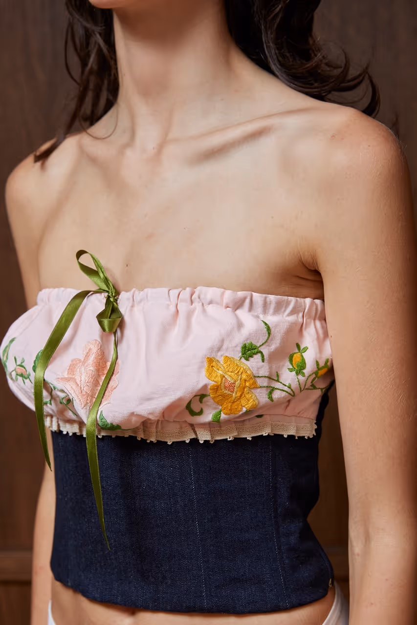 Denim bustier with vintage embroidered napkin, lined and cinched with satin ribbon, denim lined and structured with boning, side zipper. Denim : 98% cotton - 2% lycra Napkin : 100% cotton
Lining : 100% cotton Dry Cleaning Only Made in South of France The embroidered napkin is a unique piece. 