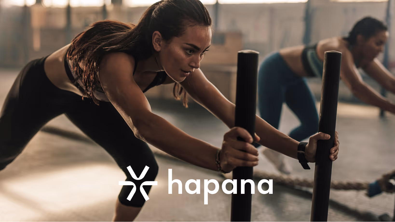 gym members pushing sled in group fitness class