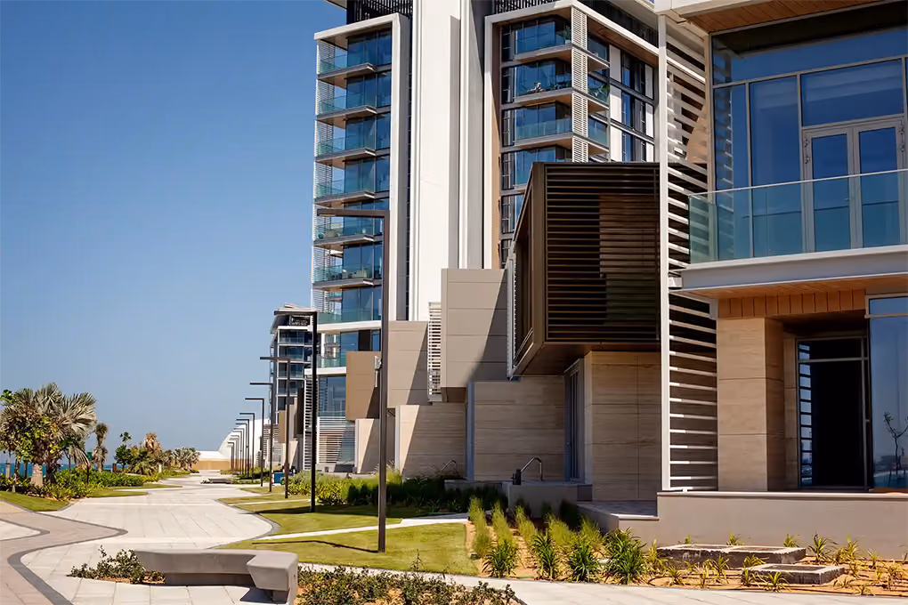 Modern tall glass apartments along a paved path with street lights