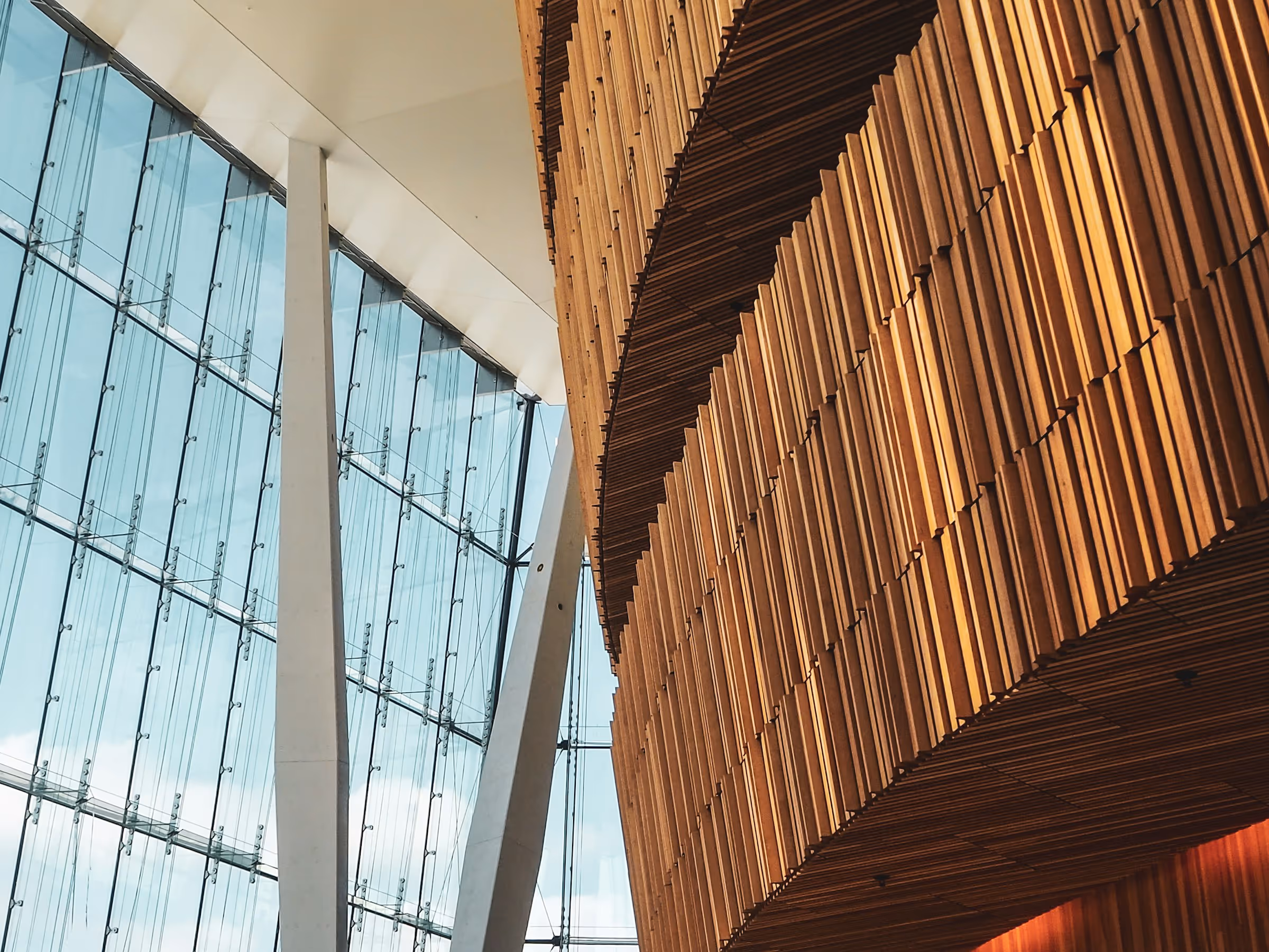 Interior of building with glass windows on the left side and wooden accent feature on the right side.