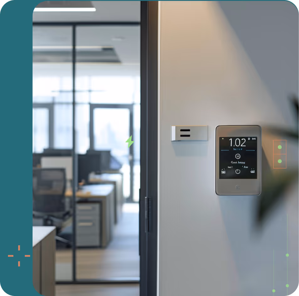 Smart thermostat mounted on a wall in a modern office with glass partitions and desks in the background.