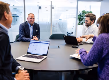A team is sitting around a table in the office discussing work processes