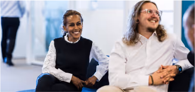 A man and a woman are sitting on the couch and smiling
