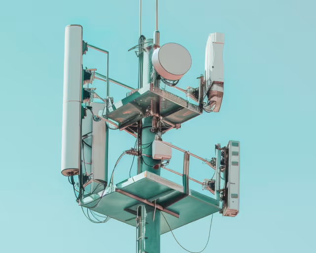 Close-up of a telecommunications tower with multiple antennas against a clear blue sky.