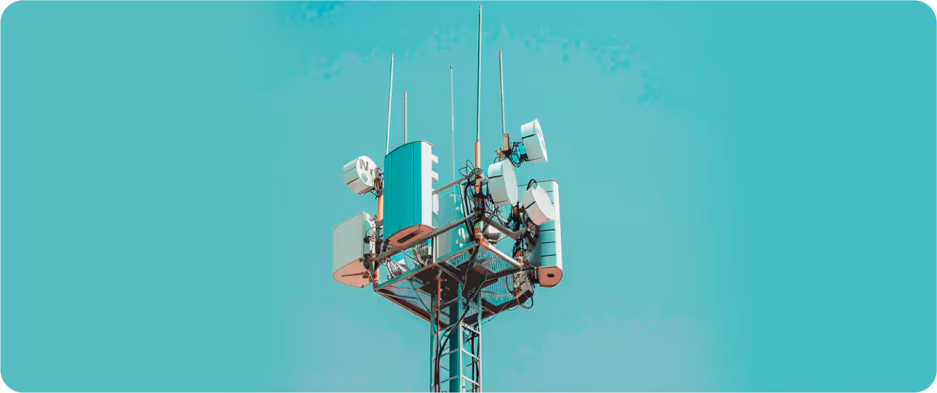 Telecommunication tower with multiple antennas and dishes against a clear blue sky.