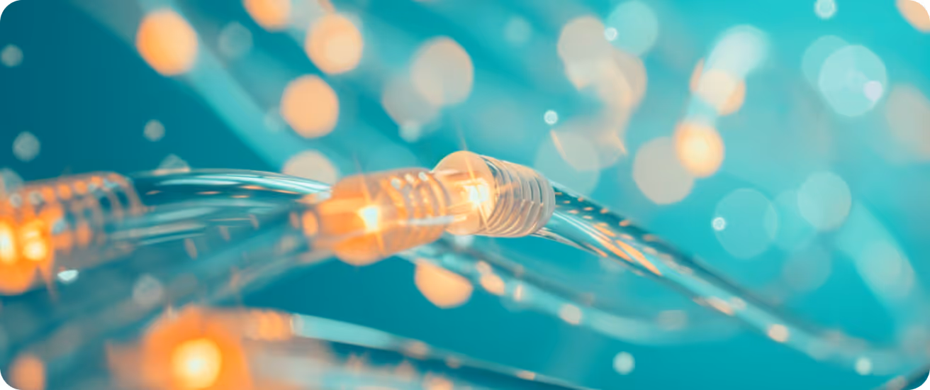 Close-up of glowing fiber optic cables with blurred turquoise and orange light bokeh background.