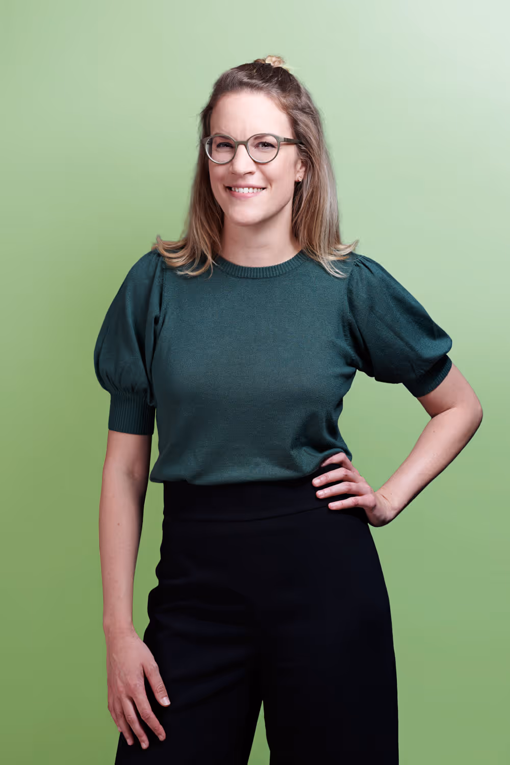 Die Rechtsanwältin von Jusonline Pascale Ruckstuhl steht dynamisch und lachend vor farbigem Studiohintergrund.