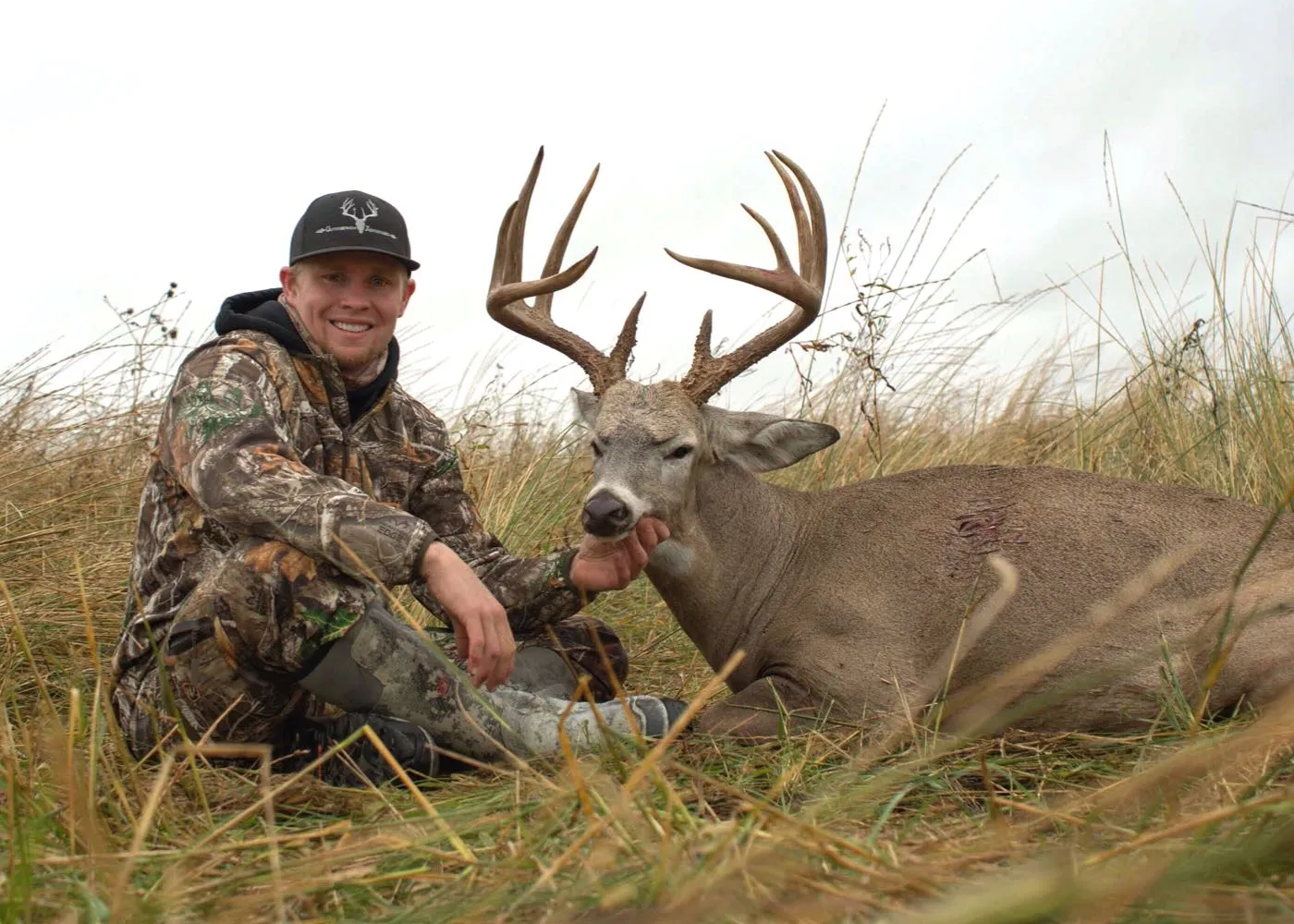 hunter with trophy buck in field