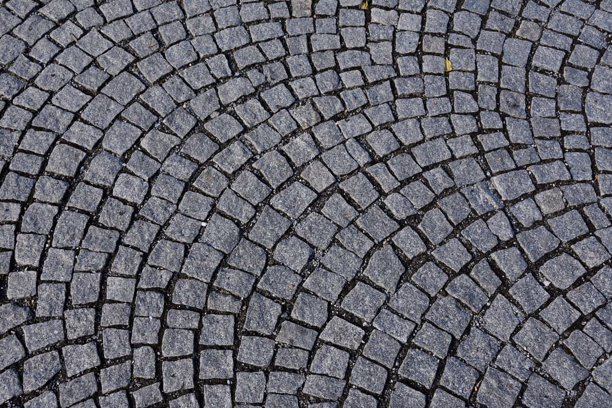 Detail obloukové dlažby z tmavé žulové kostky v Priessnitzových léčebných lázních v Jeseníku.