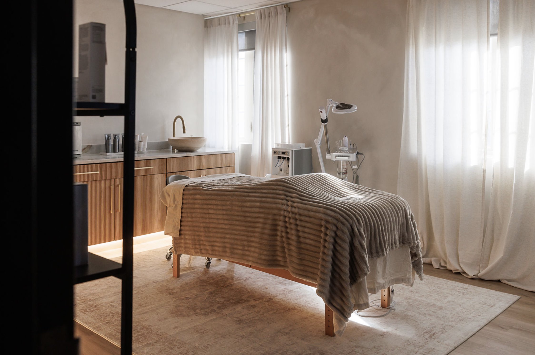 Woman with a pink towel on her head looking at her face in a handheld mirror.