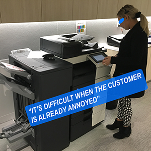 A photo of a woman standing in front of a photocopier, waiting for documents to be printed.