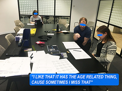 A photo of a woman testing a paper prototype while two other people take notes.