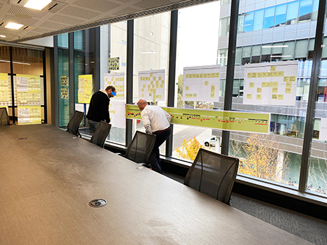 A photo of a manager and a subject matter expert looking at a user journey placed on a window.