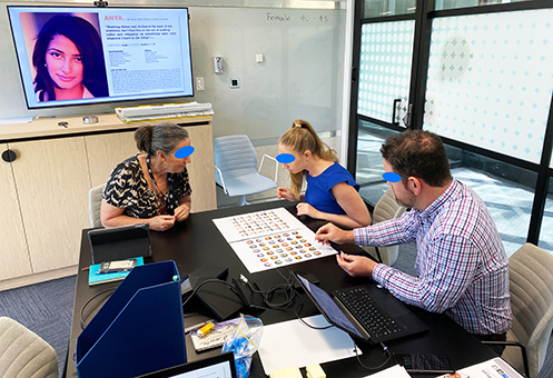 A photo of three people developing a persona's artefact on a desk.