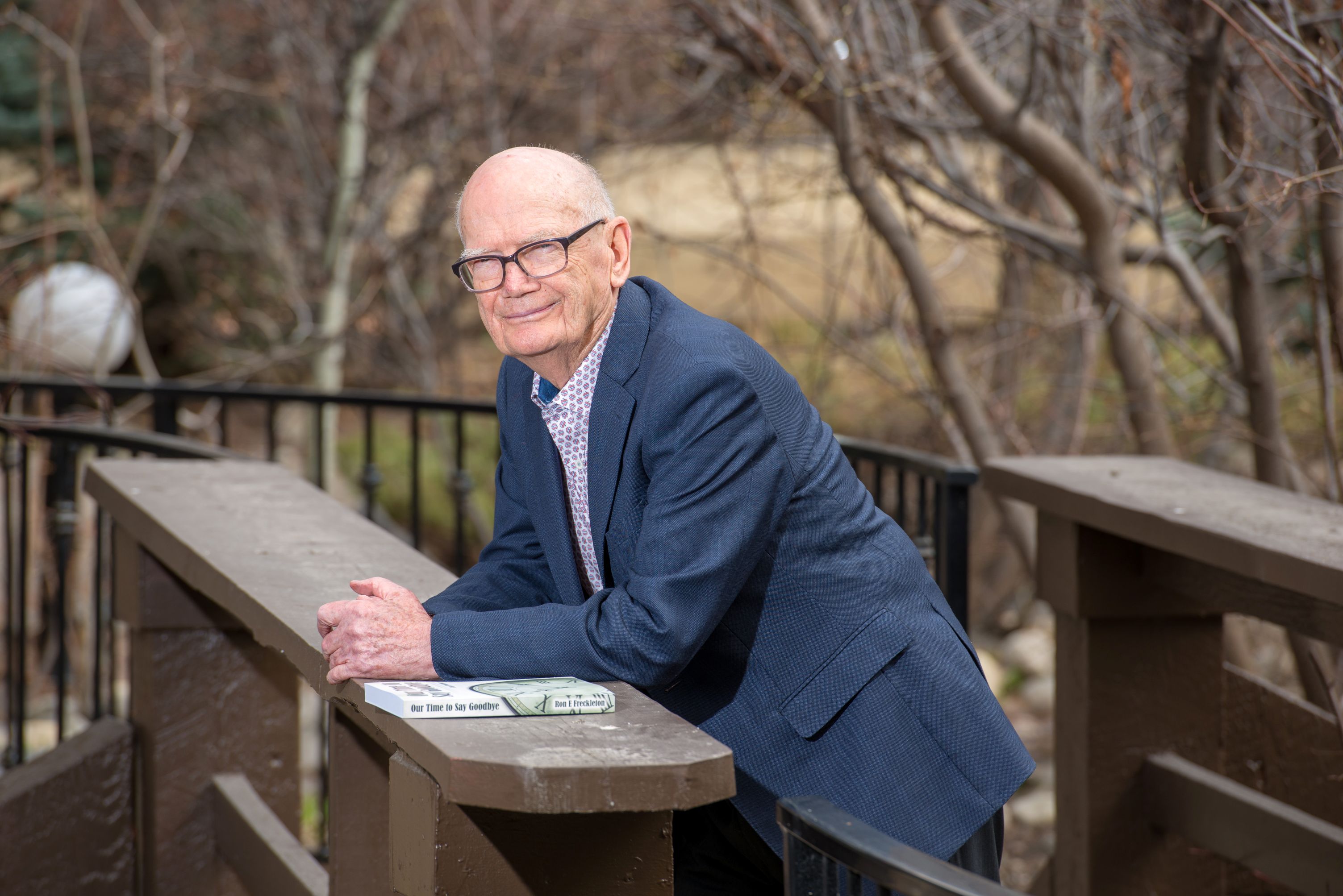 Ron Freckleton leans on a boardwalk bridge smiling