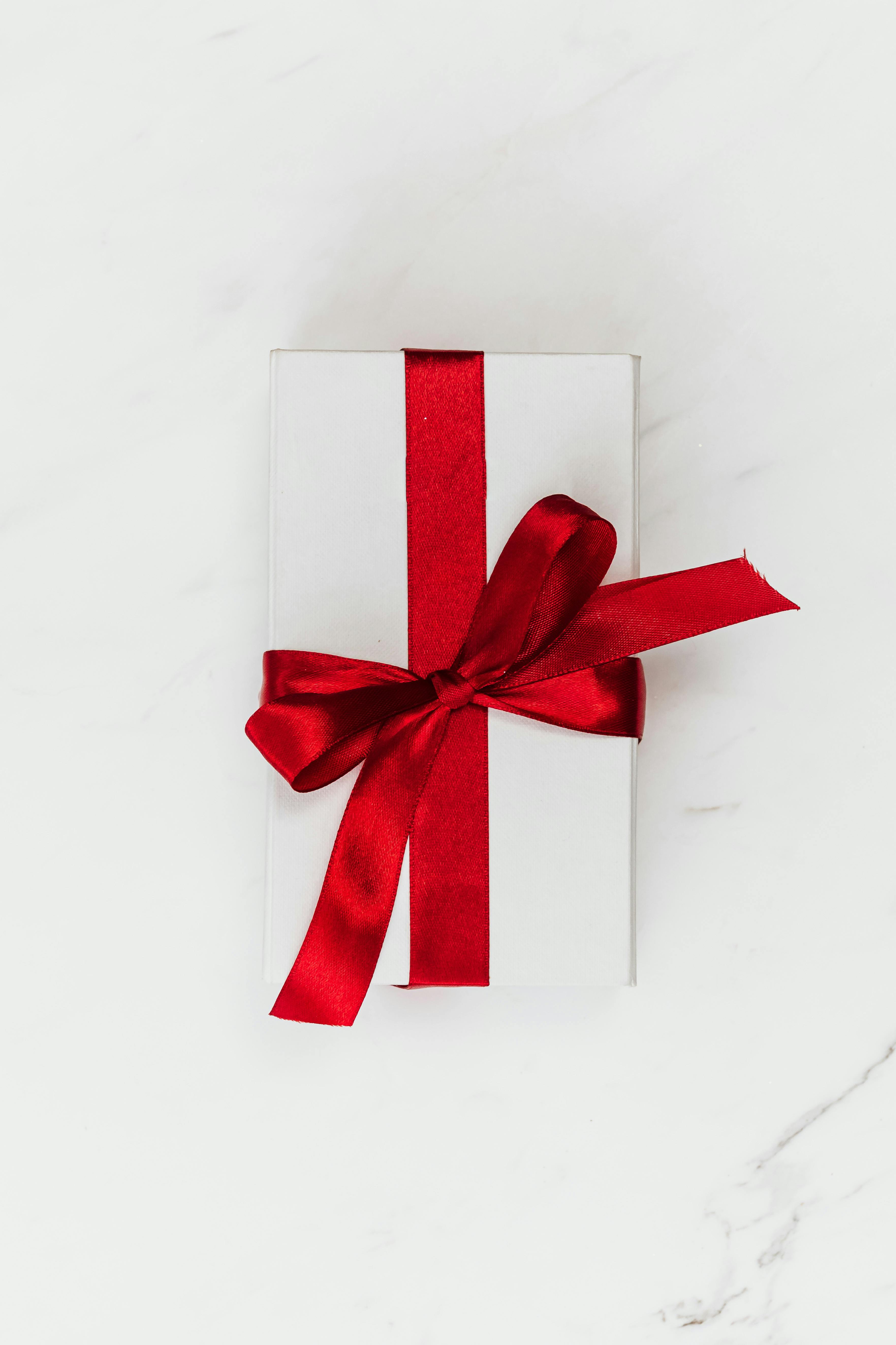 a box wrapped in white paper with a red ribbon bow
