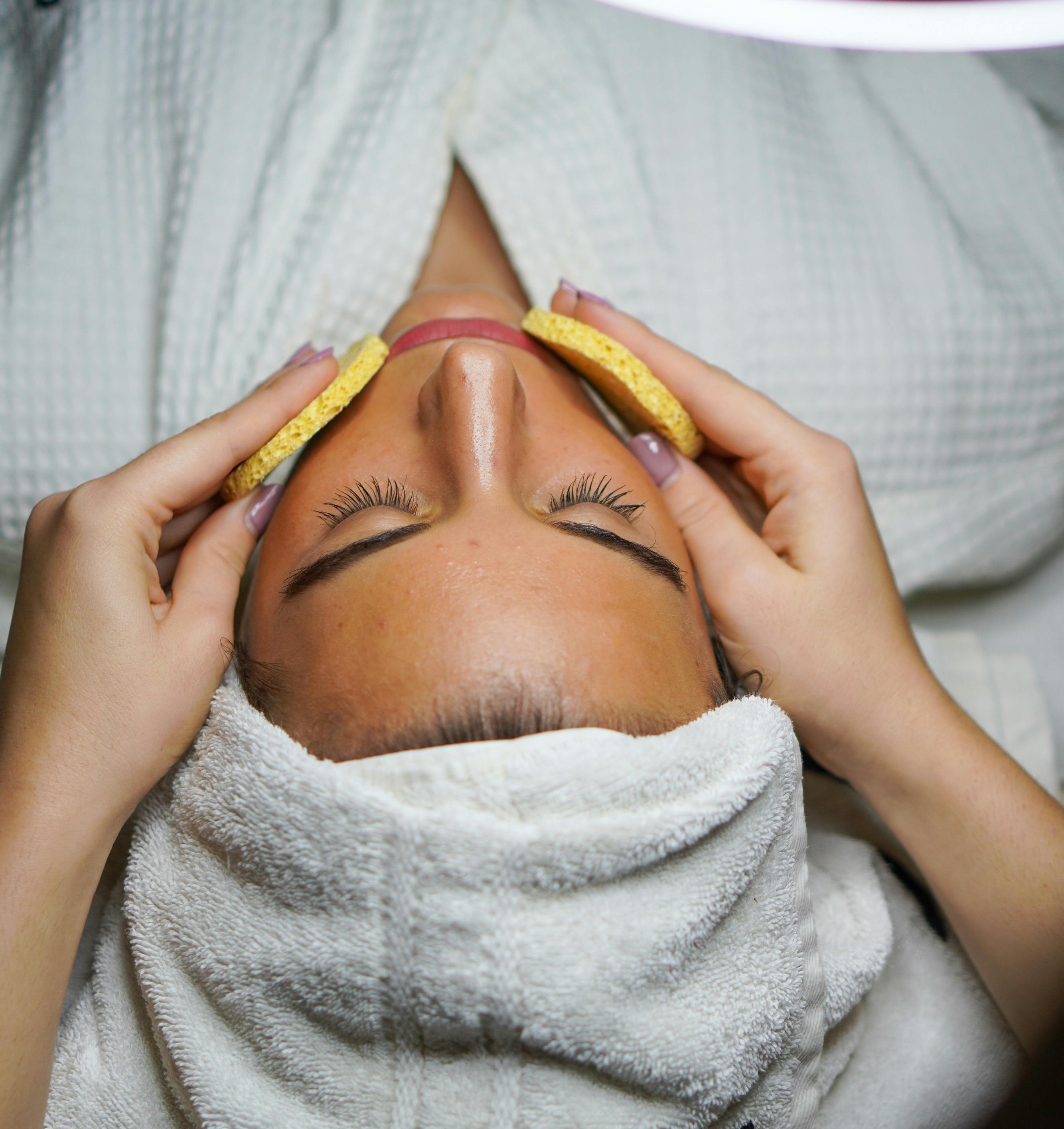 Overhead of woman at spa with towel, rob and facial treatment in progress