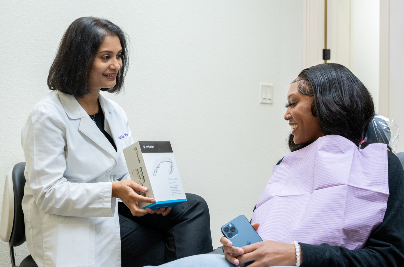 A dentist presenting Invisalign gear to a patient.