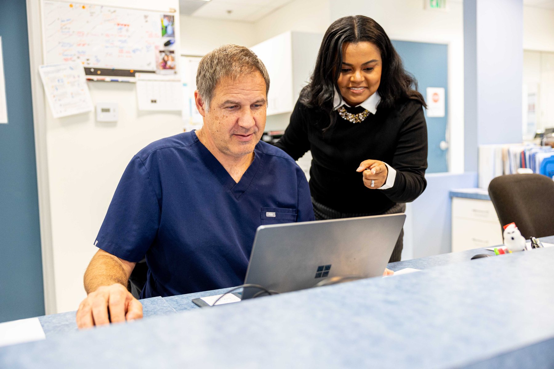 A physician and a program director reviewing a chart at the nurses station