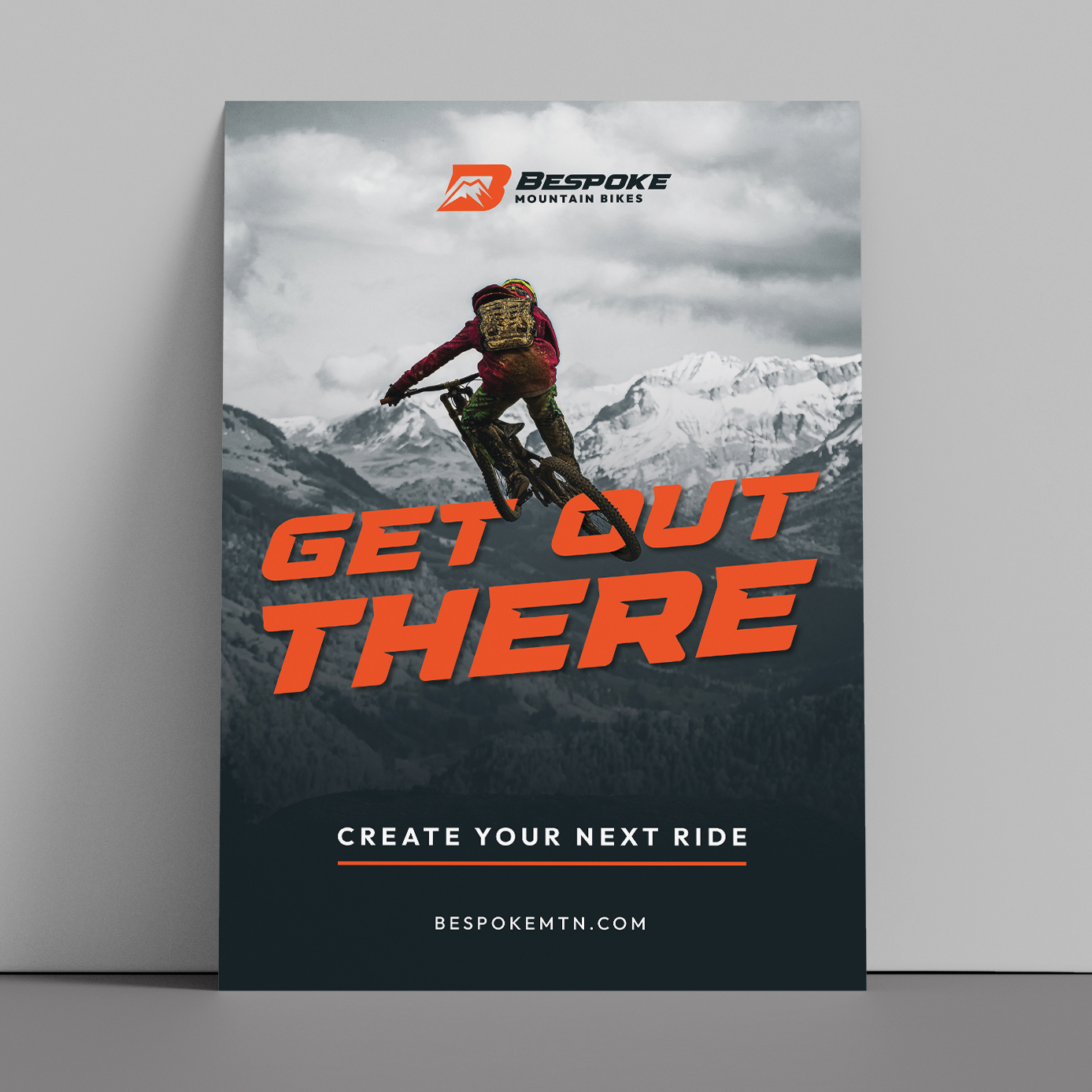 A print ad design for Bespoke Mountain Bikes featuring a mountain biker jumping in the air and the text, "Get Out There." The bottom says, "Create Your Next Ride."