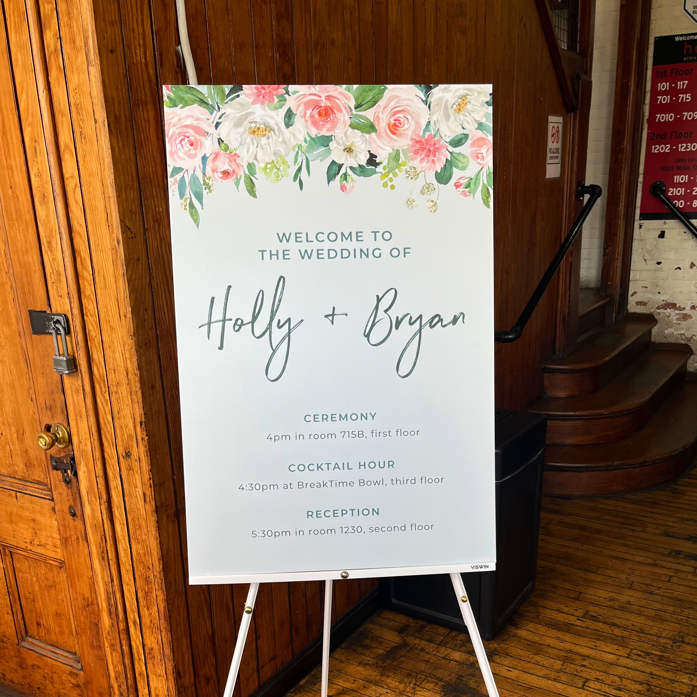 Photo of the wedding schedule sign. Features watercolor flowers at top and text that says "Welcome to the wedding of Holly and Bryan. April 13th, 2024," followed by times and locations for the events for the day