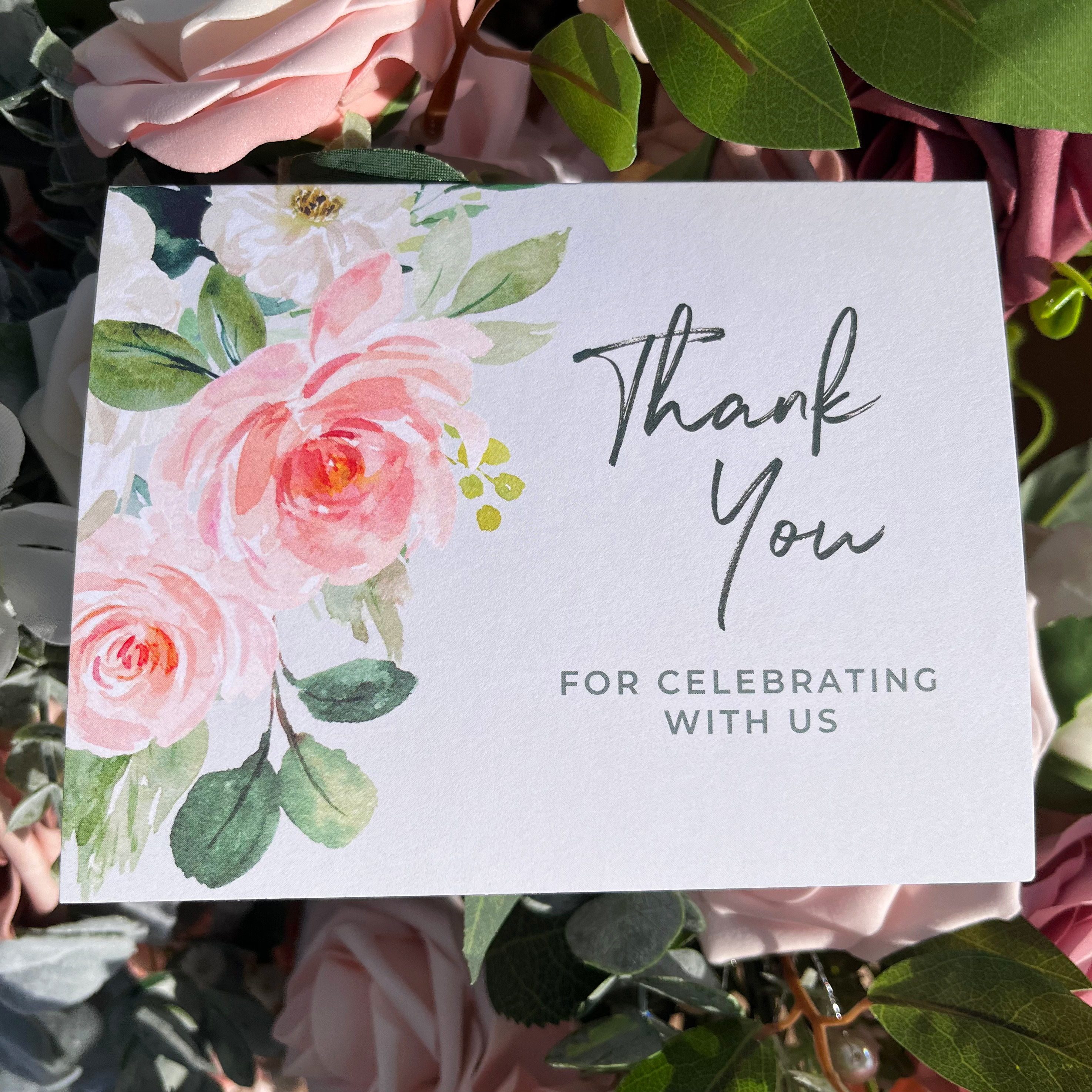 Photo of the wedding thank you card. Features watercolor flowers in the corners and text that reads, "Thank you for celebrating with us"