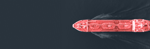Top-down view of a red-shaded cargo ship sailing through dark blue water.