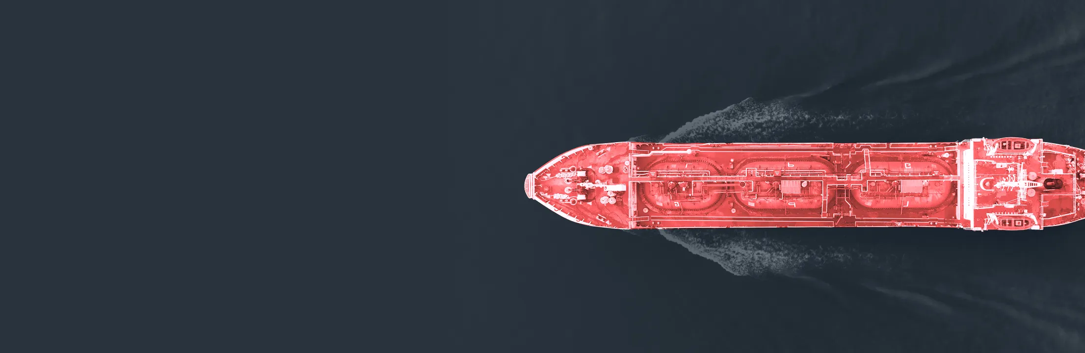 Top-down view of a red-shaded cargo ship sailing through dark blue water.