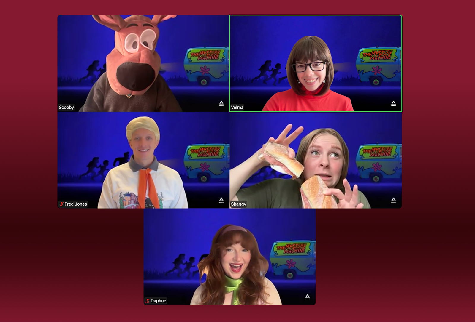 A virtual meeting grid displays five participants in Scooby Doo costumes and expressions. The top row features a person wearing a large Scooby Doo hat, smiling, another with round glasses and red sweater, and a third person waving. The bottom row shows a participant dressed in a white shirt with an orange necktie, holding food, and a person with long hair in character attire, also smiling.